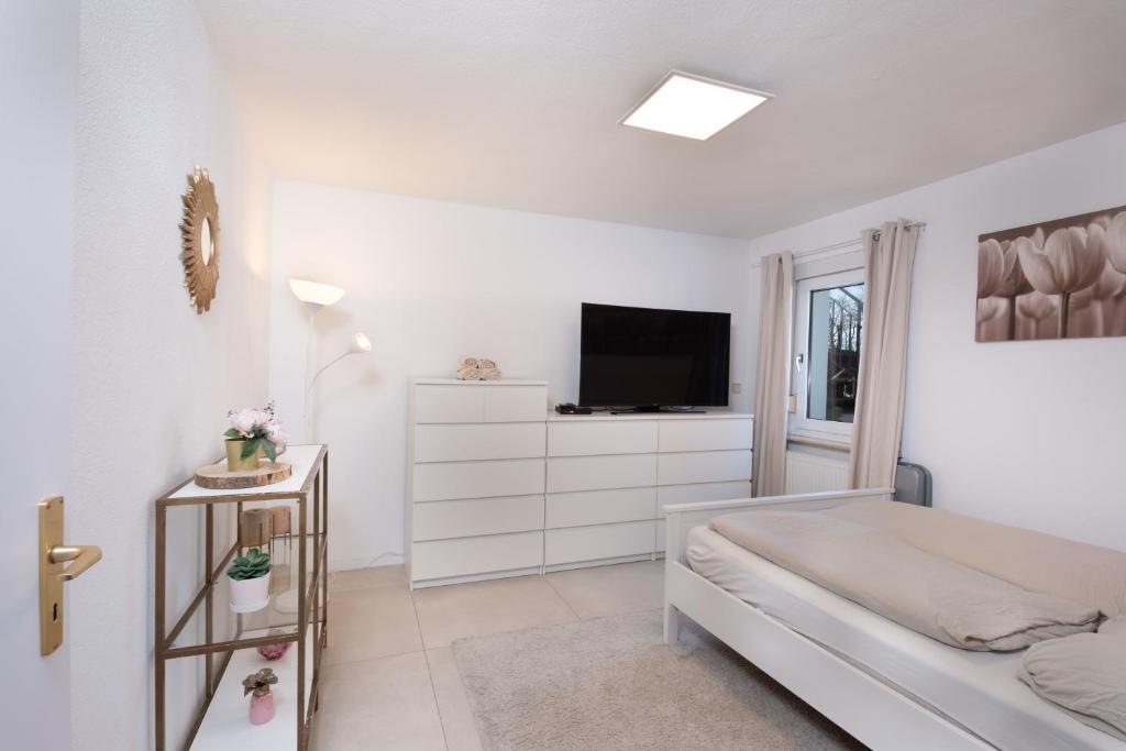 a white bedroom with a bed and a television at Schöne moderne 2-Zimmerwohnung in Göppingen