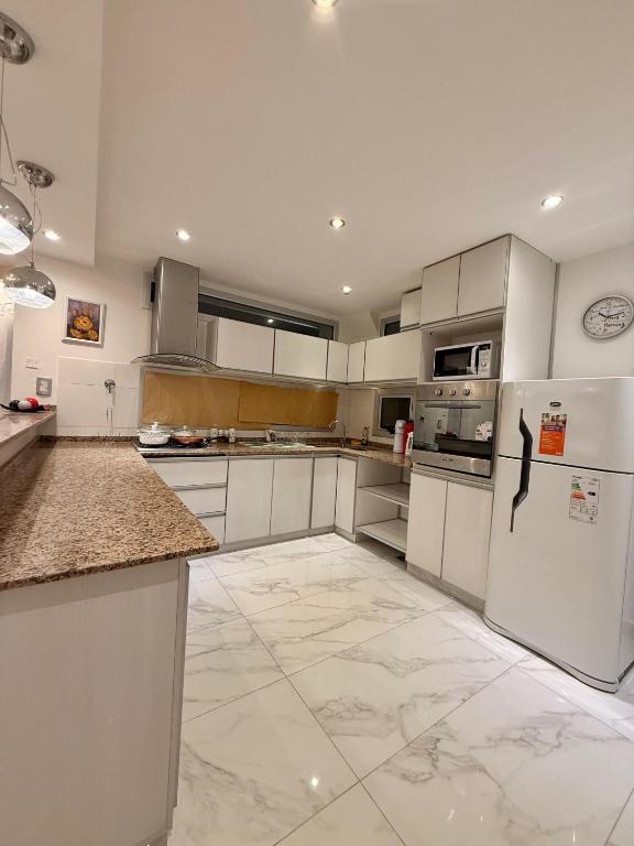 a large kitchen with white cabinets and appliances at Jardines del Liceo in Comodoro Rivadavia