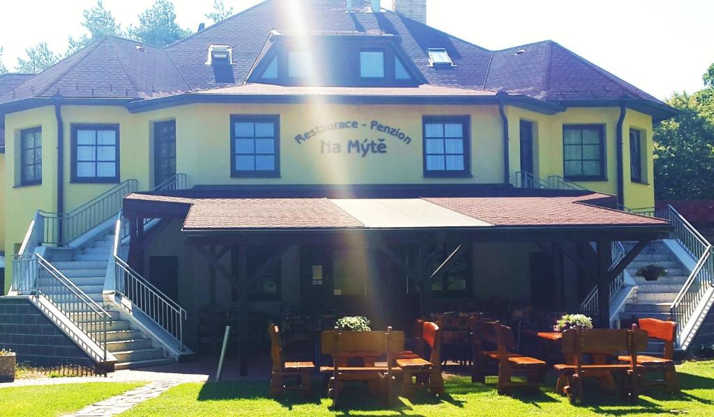 a yellow house with tables and chairs in front of it at Penzion - Restaurace Na Mýtě in Sezimovo Ústí