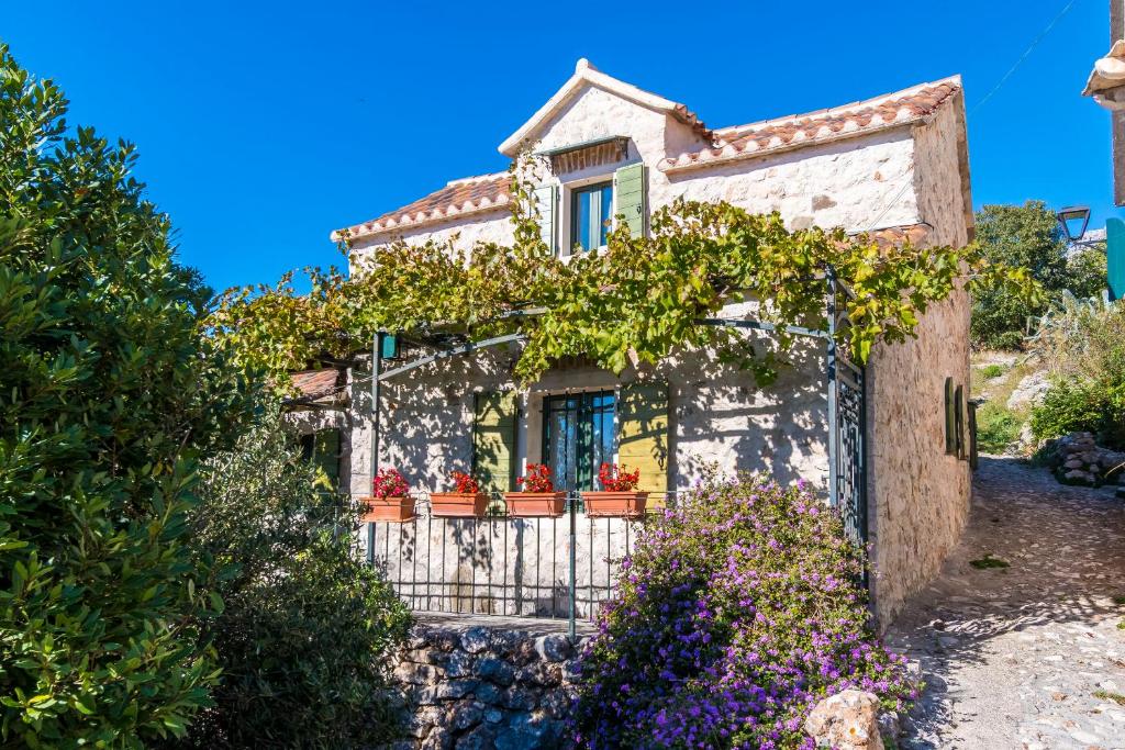 a small house with flowers in front of it at House Dobrila in Igrane