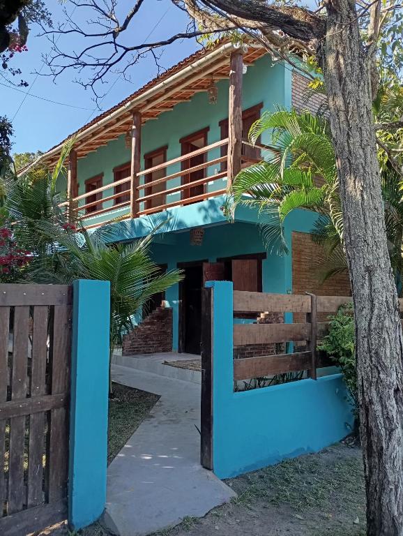 a blue house with a fence and a tree at Pousada Mestre Lua - Itaúnas in Conceição da Barra