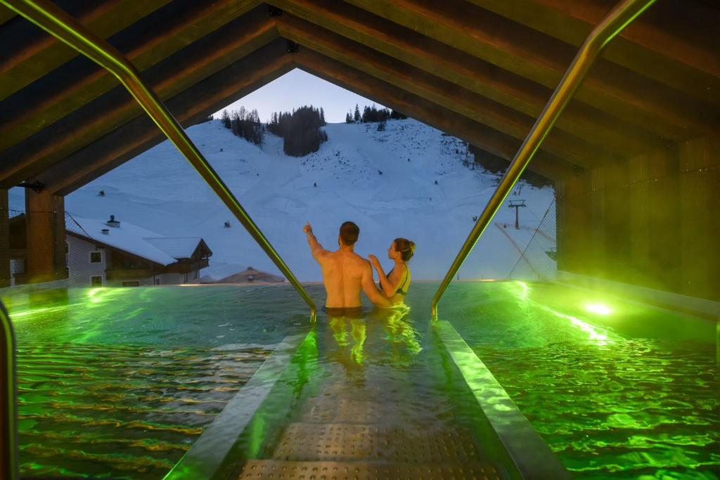 a man and a woman sitting in a swimming pool at Hotel Zauchensee Zentral in Zauchensee