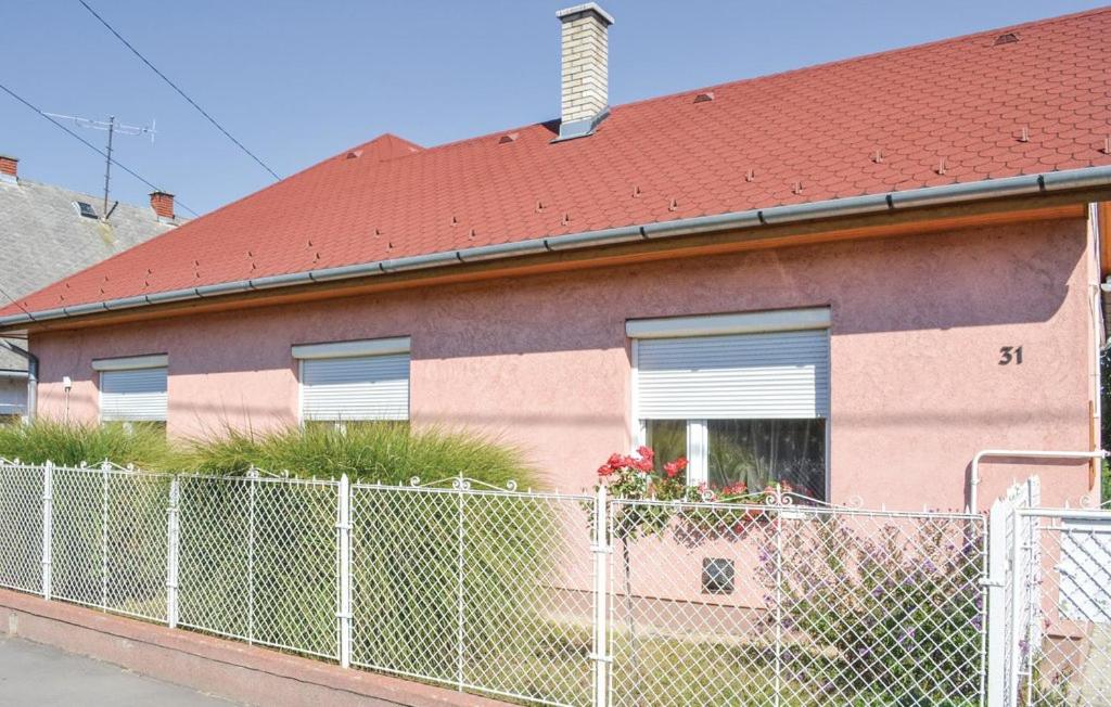 a pink house with a fence in front of it at Beni Apartman in Balatonlelle