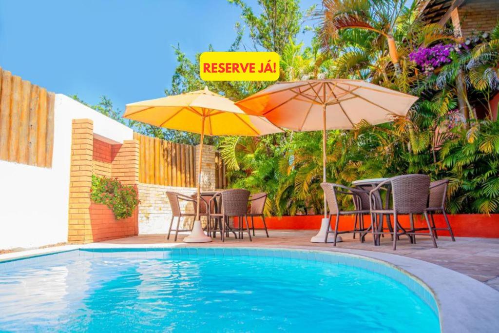 a swimming pool with chairs and umbrellas and a table and chairs at Garbos Soleil Hotel in Natal