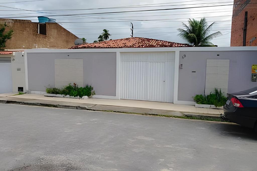 a white house with four garage doors on a street at Casa em Maceió Para Alojamento ou Família Grande in Maceió