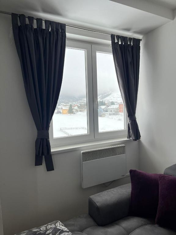 a living room with a window with blue curtains at Apartman Zimski Kutak in Kupres