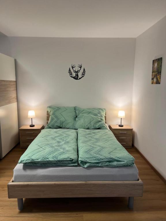 a bedroom with a bed with green sheets and two lamps at Apartment Sebald in Ingolstadt