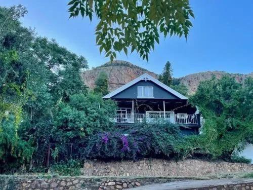 a house sitting on top of a hill with trees at Shekinah Cabin in Hartbeespoort