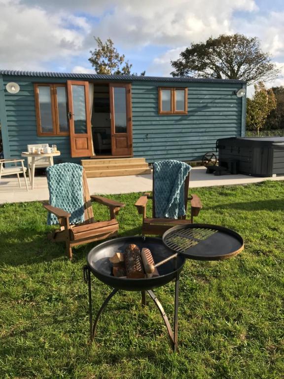 a tiny house with a table and chairs in the yard at Ty Beti at Gorlan yr Efail Shepherds Hut with Private Hot Tub in Holyhead