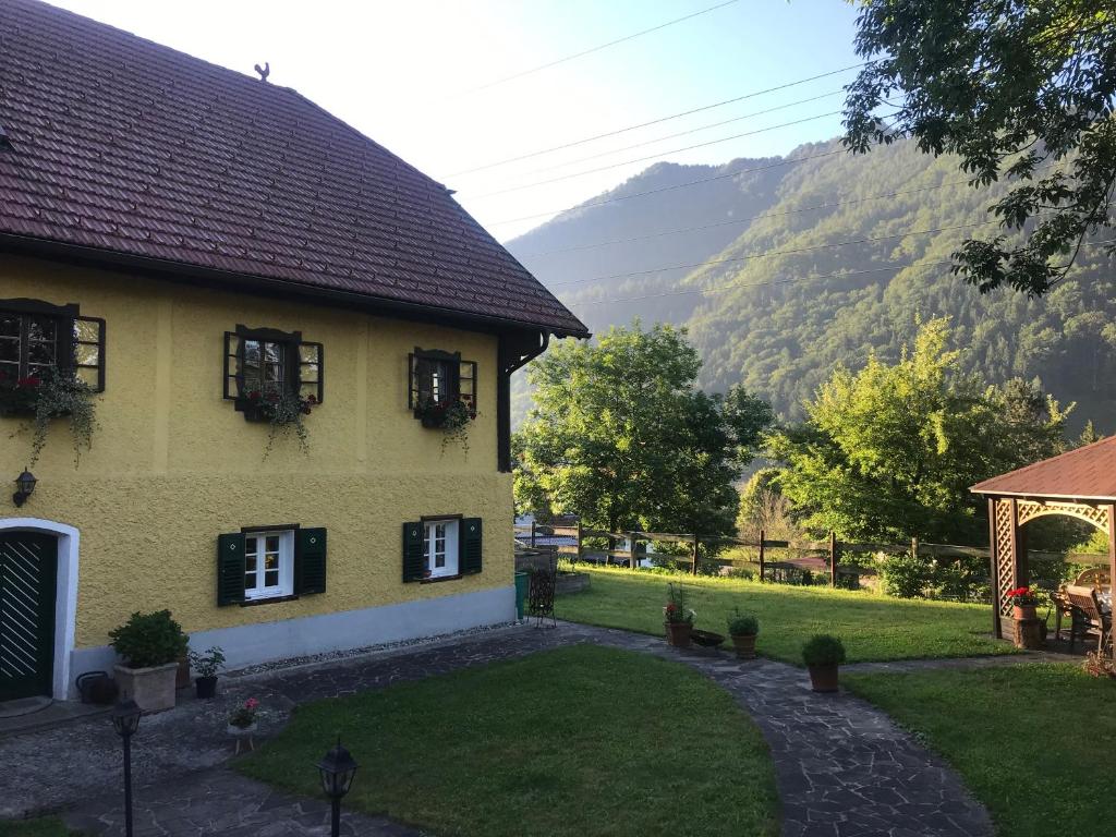 a yellow house with a garden and mountains in the background at Reitterhof in Laufnitzdorf in Frohnleiten