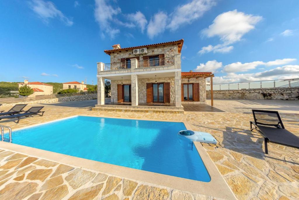 a villa with a swimming pool in front of a house at Sunset Vista Villas Classic I in Volímai