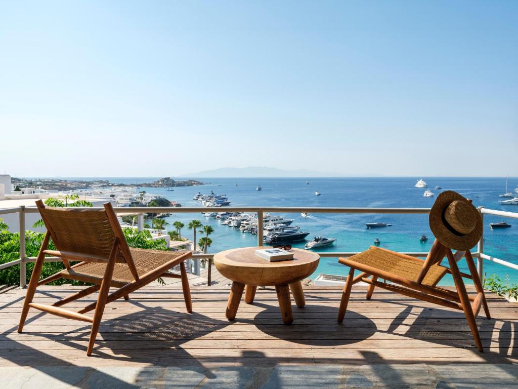 a patio with chairs and a table and a view of the ocean at Trinitas Mare Psarou Beach in Psarou