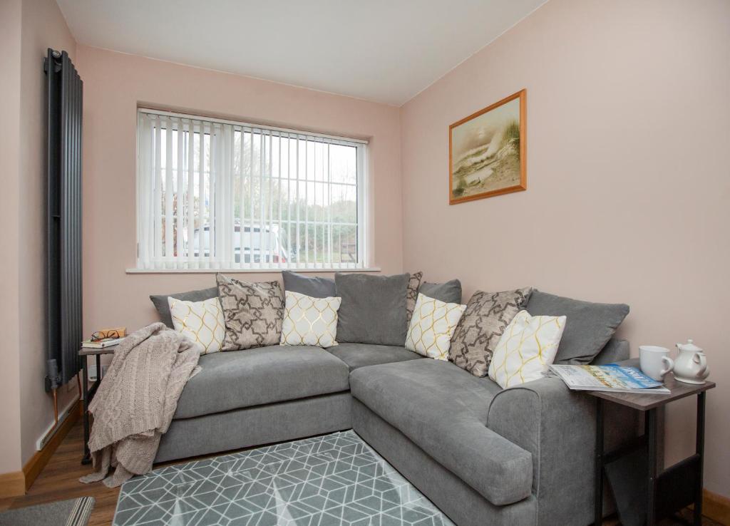 a living room with a gray couch and a window at The Annex @ 136 in Gloucestershire