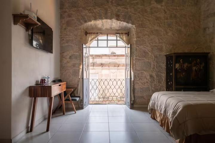 a bedroom with a bed and a table and a window at Casa Alzate in Morelia