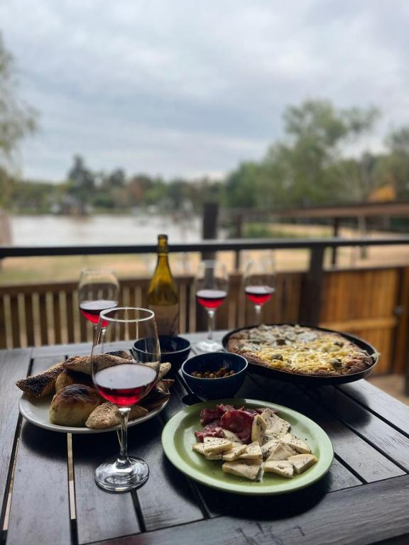 a wooden table with two plates of food and glasses of wine at Cabaña DEK in Tigre