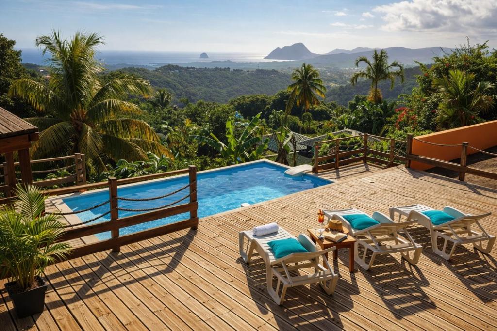 a deck with a pool and chairs and a view at Villa CosaRoé-Vue Mer-Piscine-3 étoiles in Rivière-Salée