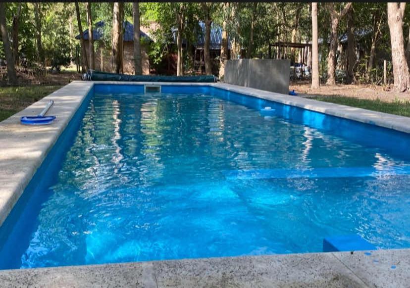 a swimming pool with blue water in a yard at Quinta con pileta in Brandsen
