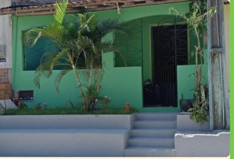 a green building with stairs and a palm tree at Casa da gamboa in Cairu