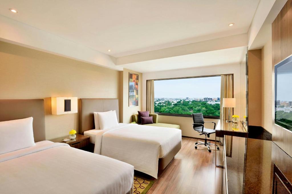 a hotel room with two beds and a window at Courtyard by Marriott Chennai in Chennai