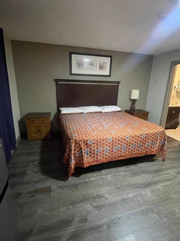 a bedroom with a bed with an orange comforter at Western Lodge Phoenix Airport/Downtown in Phoenix