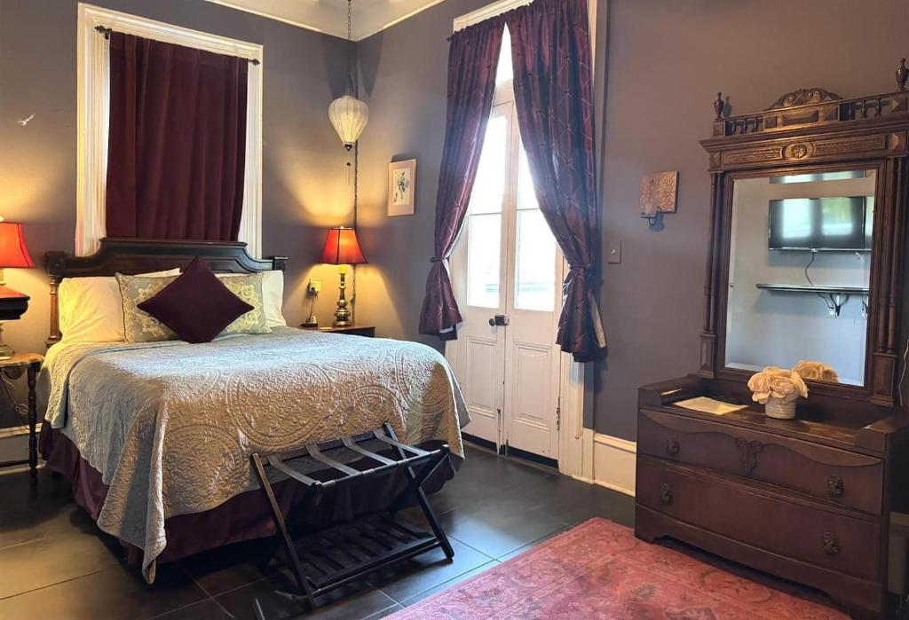 a bedroom with a bed and a dresser and a window at The Dragonfly Tremé-Historic Guesthouse-Near French Quarter in New Orleans