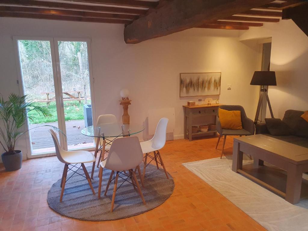 a living room with a glass table and chairs at Gîte Les Fourmilières in Ligny-le-Ribault