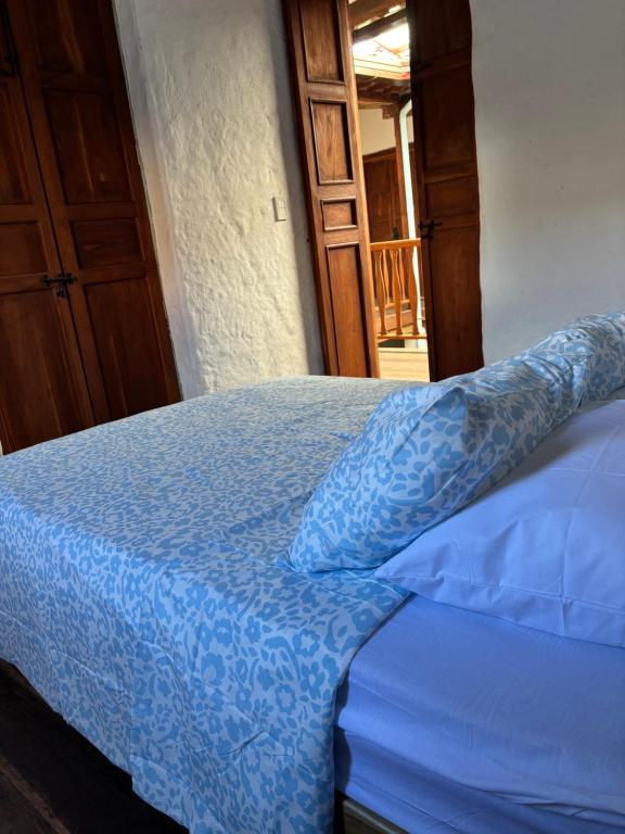 a bed with a blue comforter and pillows at Casona El Nacional in San Gil