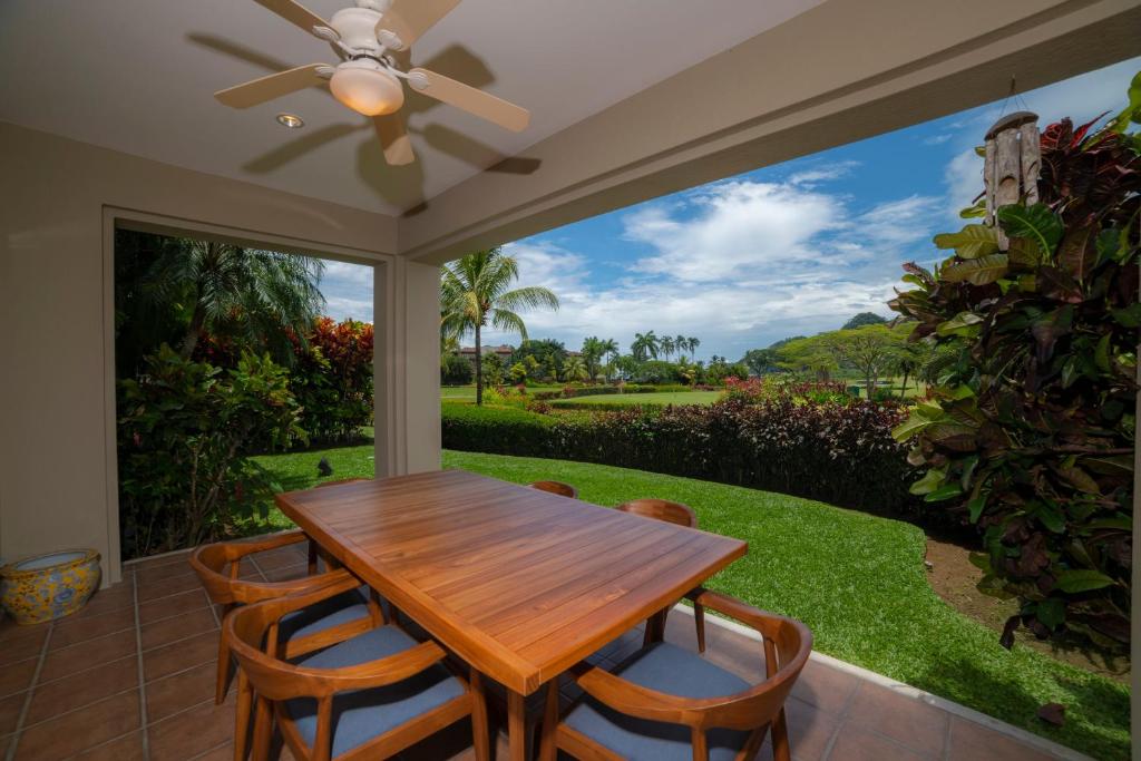 a screened in porch with a wooden table and chairs at Del Mar 4N 3 bdr Garden View in Los Suenos in Herradura