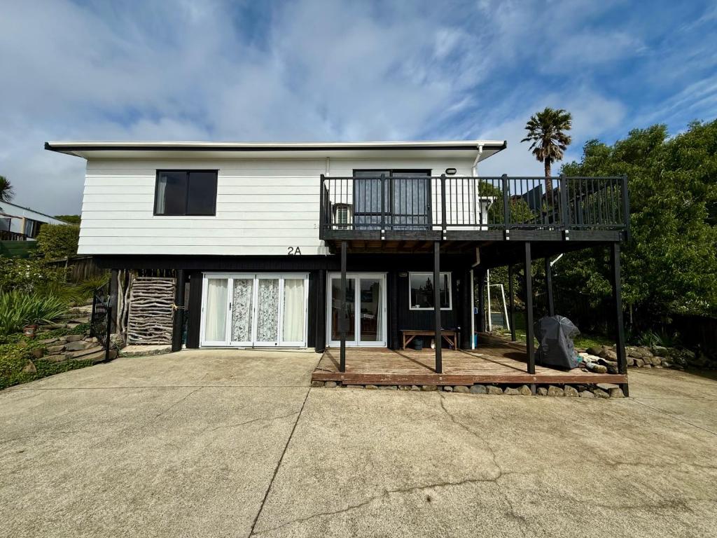 a house with a deck on top of it at Cosy Raglan Studio - Walk to Beach and Village - Roberts St - Studio Downstairs in Raglan