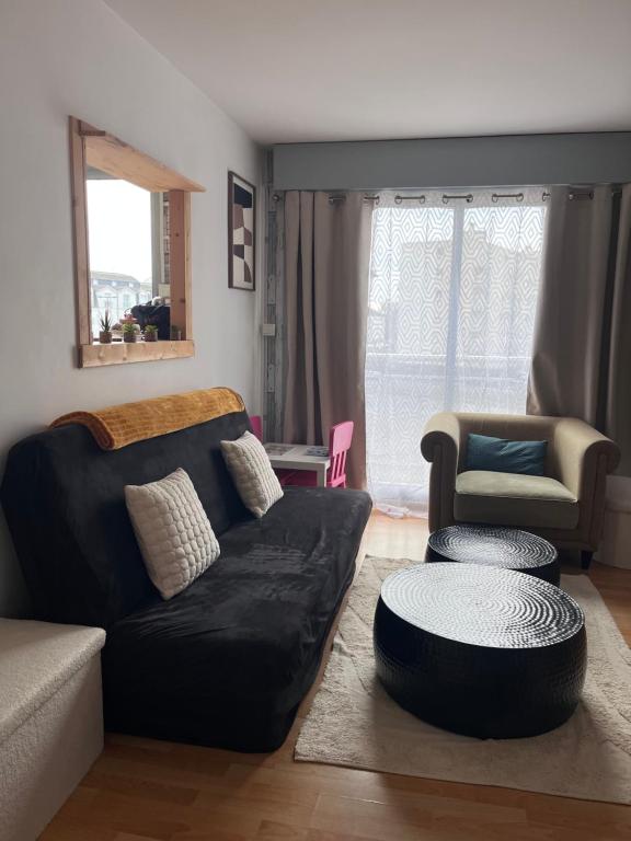 a living room with a black couch and a chair at Ma première étoile in Joué-lès-Tours