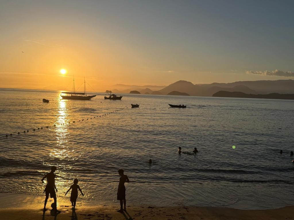 a group of people on the beach at sunset at Deck Picinguaba Pousada in Picinguaba
