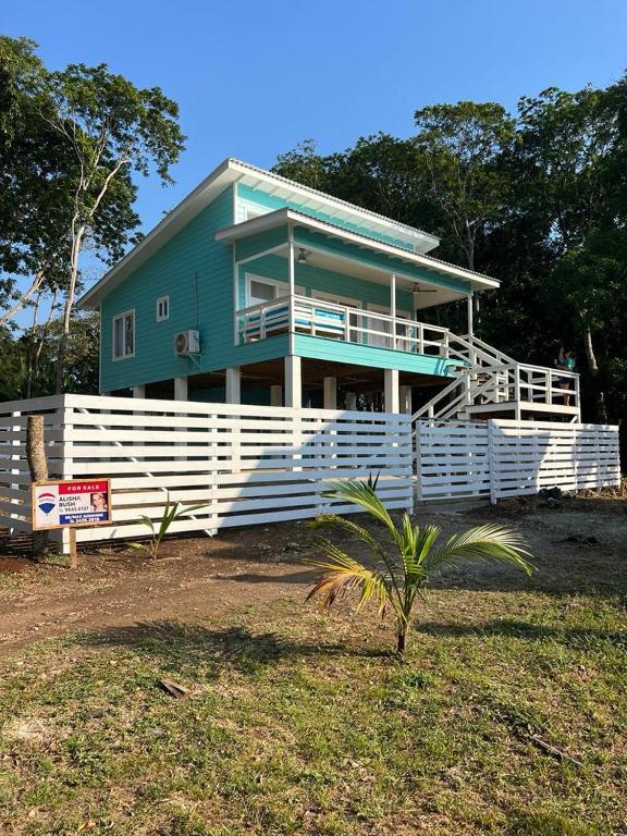 a blue house with a white fence in front of it at Island Time house in Utila