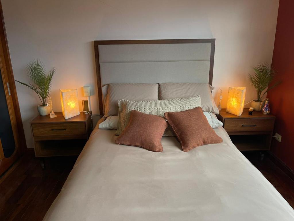 a large white bed with three pillows and two lamps at Casa Sosa in Zacatlán