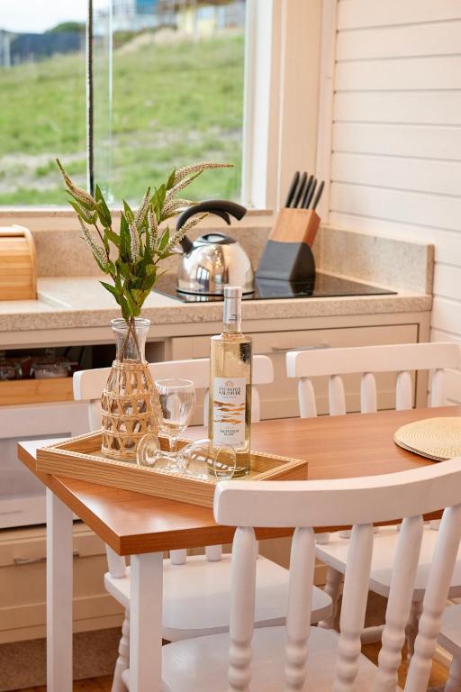 a table and chairs with a bottle of wine on it at Encantos de Altitude Cabanas e Studio Container in São Joaquim