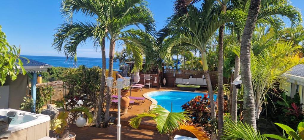 a resort with a swimming pool and palm trees at Les Gîtes Blue Karaib in Sainte-Anne