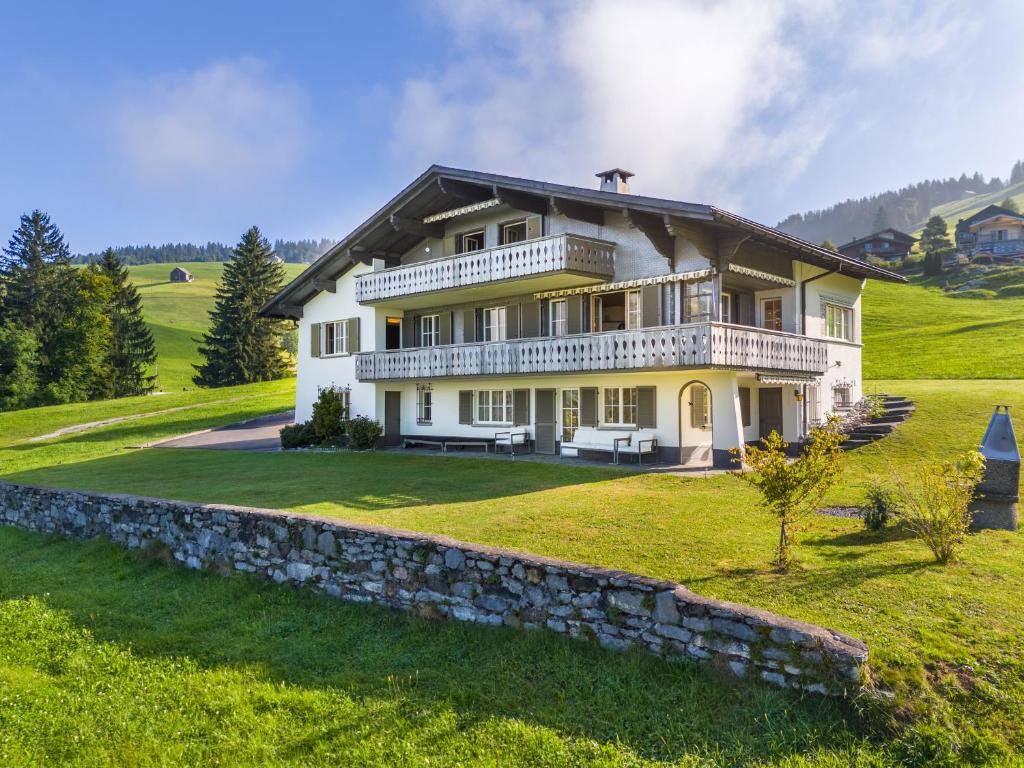 a large white house with a stone wall at Villa mit Seeblick in Amden