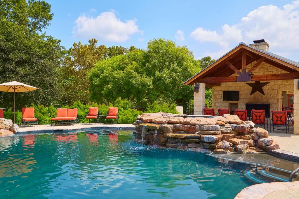 a swimming pool with a stone fireplace and red chairs at Fredericksburg Inn and Suites in Fredericksburg