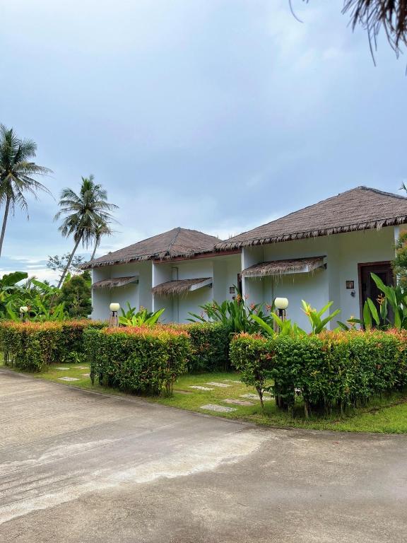 a building with trees and bushes next to a road at Phetra pool villas in Suratthani