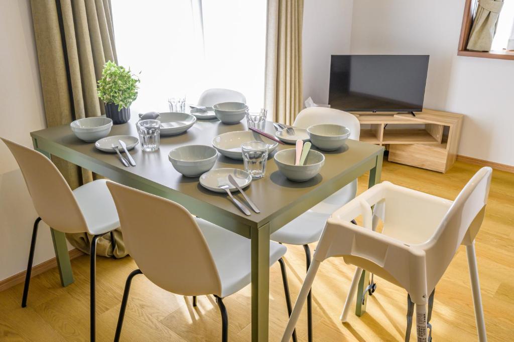 a dining room table with white chairs and a television at Chill Place 120 Ayase in Tokyo