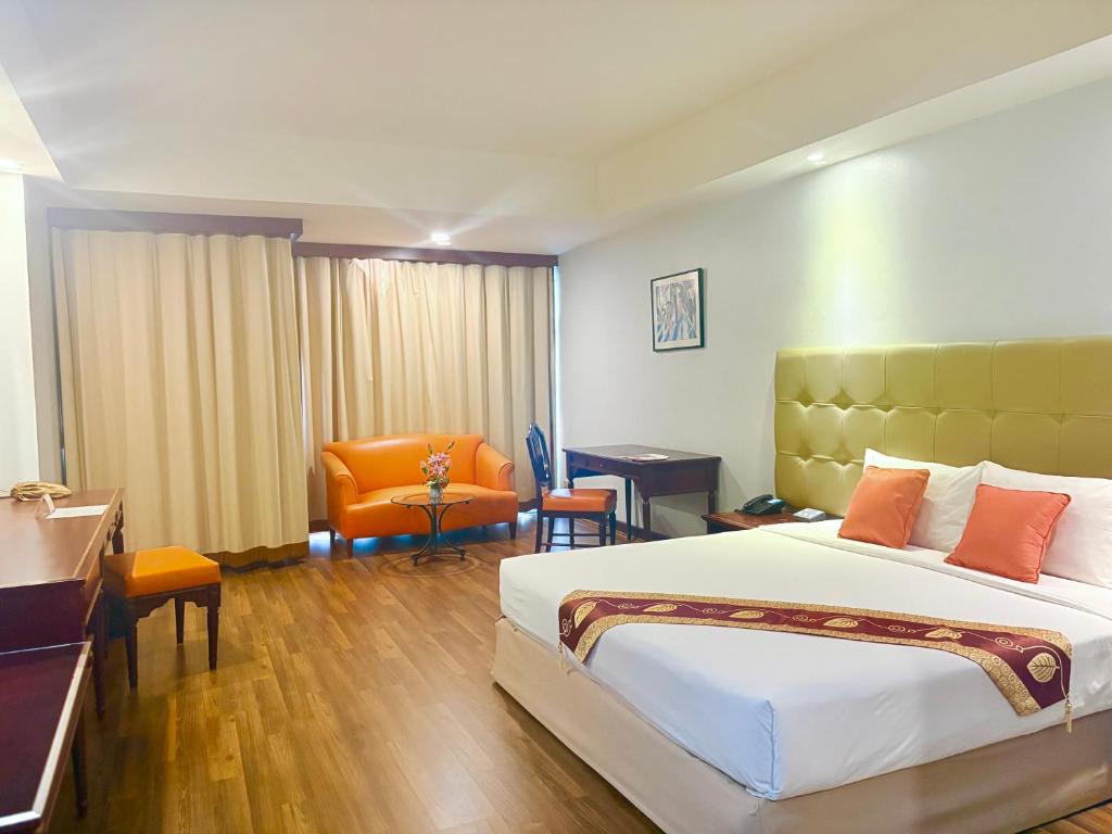 a hotel room with a large bed and a chair at Tai Pan Hotel in Bangkok