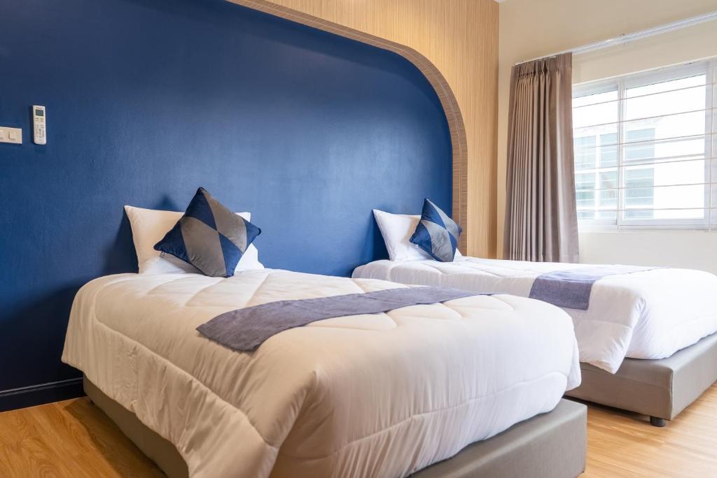 two beds in a room with a blue wall at Reach Home Hatyai in Hat Yai
