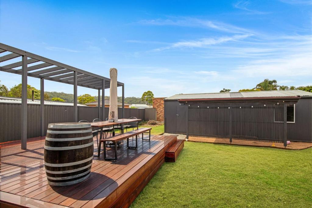 a patio with a table and a barrel on a deck at Sea Side Glide at Maloneys Hide in Maloney's Beach