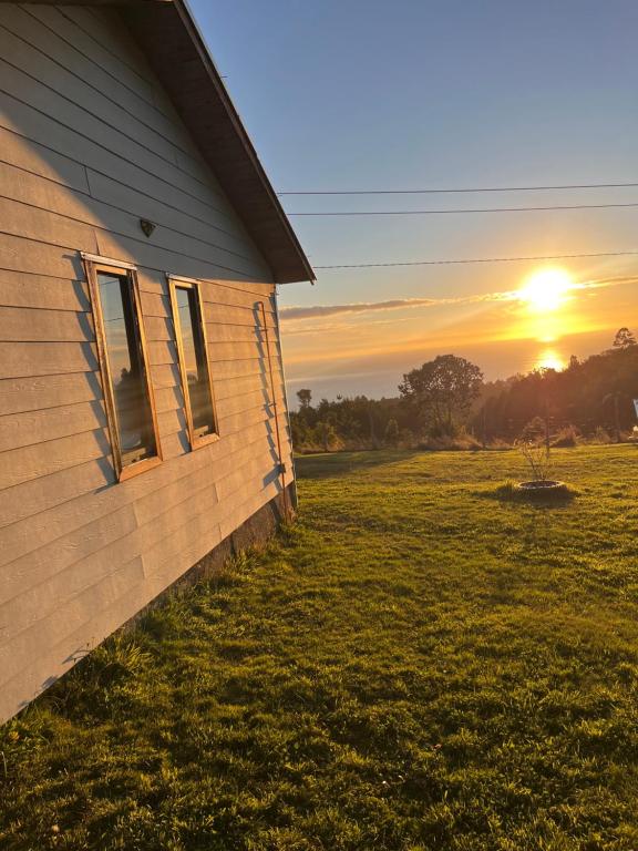 a house in a field with the sunset in the background at Cabaña arriendo Salome in Valdivia