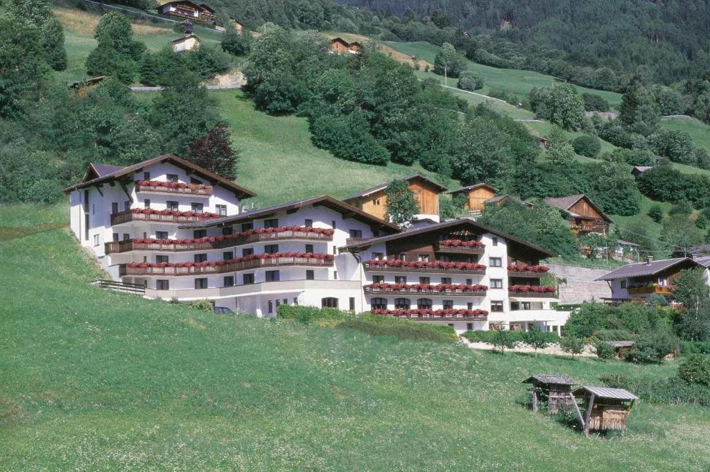 a large white building on a hill in a field at Hotel Alpenfriede in Jerzens