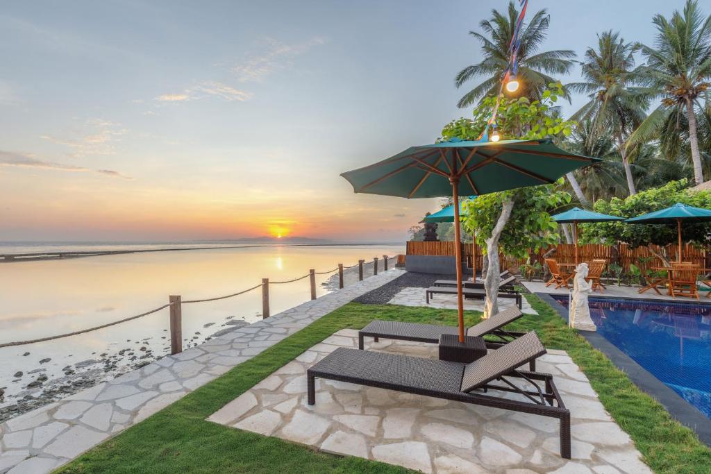 a bench with an umbrella next to a swimming pool at La Semaya Beach Villas in Nusa Penida