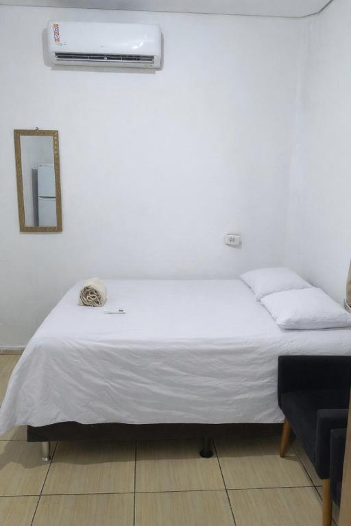 a white bed in a room with a mirror at Pousada RC Q2 in Várzea Grande