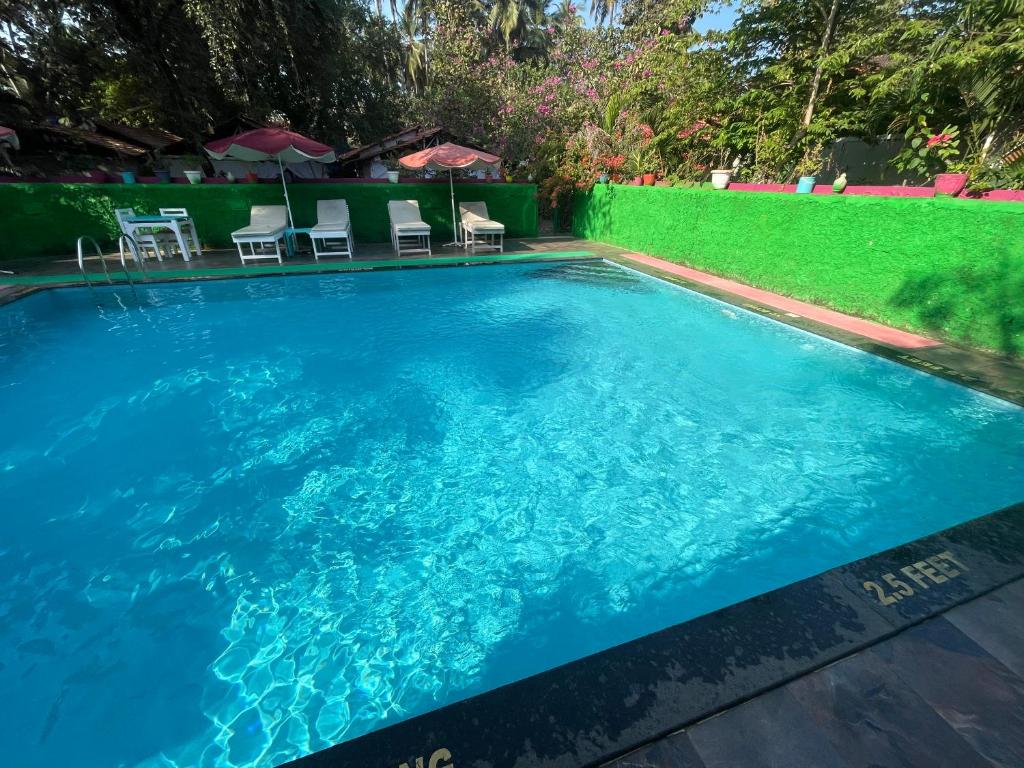 a large blue swimming pool with chairs in a yard at Art Resort Goa in Palolem