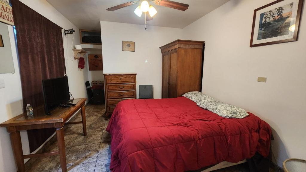 a bedroom with a red bed and a desk and a television at Vizcaino Departamento con cocina in Ensenada