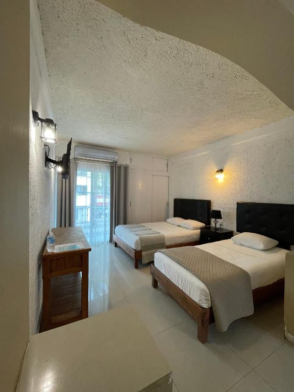 a hotel room with two beds and a window at Hotel Dos Mundos, Isla Cozumel in Cozumel