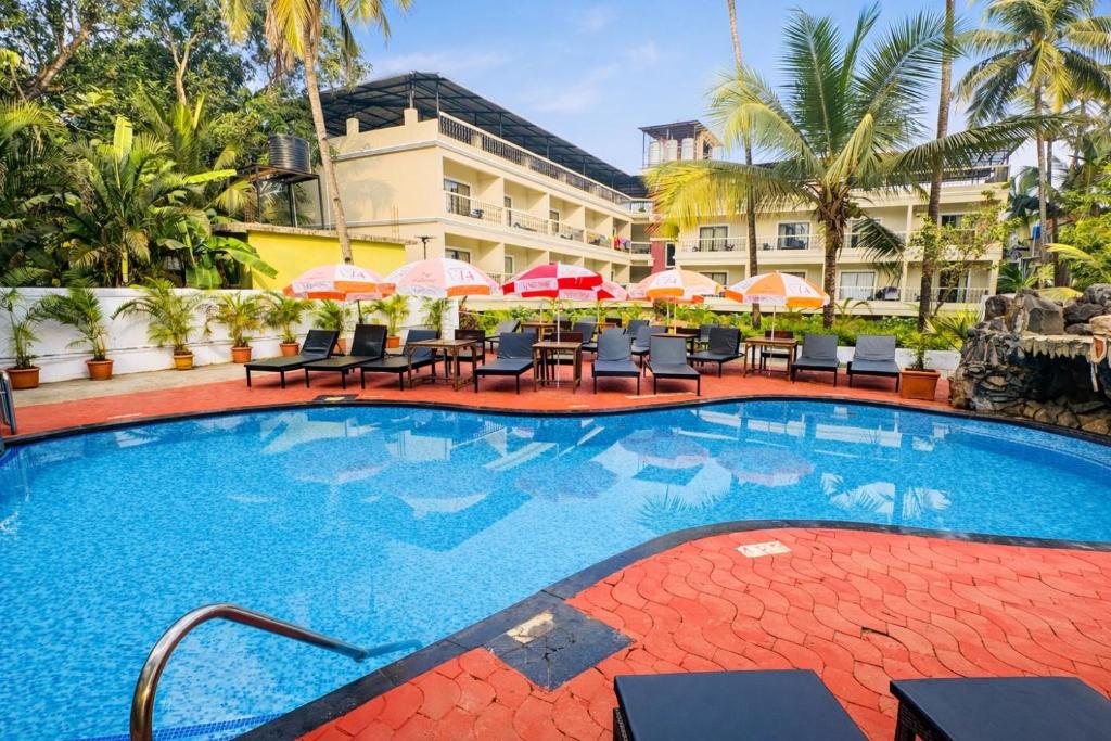 a pool at a hotel with chairs and umbrellas at Silver Sands Sunshine - Angaara in Candolim